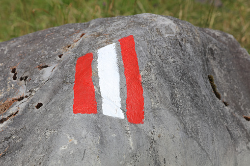 White and red trail sign painted on a Rock. Lech Valley. Austria