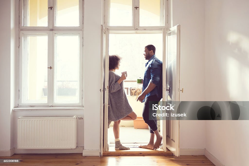 Afro american couple standing by the window at home Afro american couple talking by the window at home in the morning light, drinking coffee. Afro Hairstyle Stock Photo