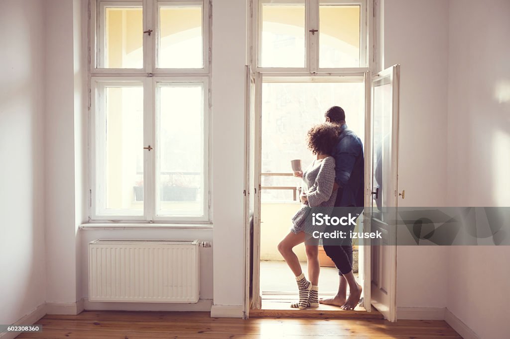 Afro american couple standing by the window at home Afro american couple embracing by the window at home in the morning light. Adult Stock Photo