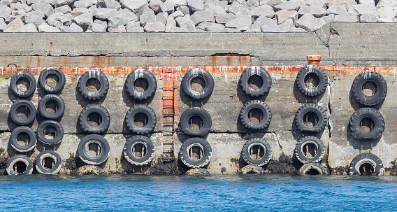 Old concrete mooring wall with car tires