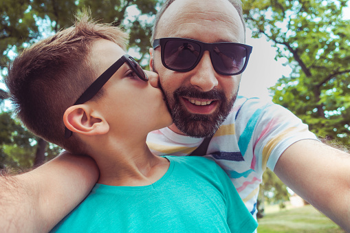 Photo of father with son in the park takes selfie with smartphone