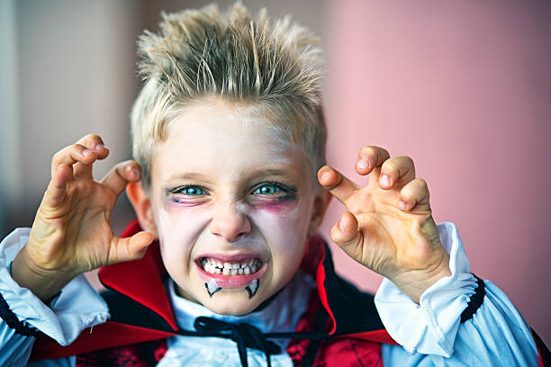 Portrait of a little boy dressed up as halloween vampire Portrait of a little boy dressed up as halloween vampire. The boy is aged 6 and is making scary face at the camera. costume stock pictures, royalty-free photos & images