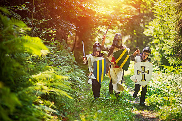 crianças brincando de cavaleiros na floresta - fighting sword knight suit of armor - fotografias e filmes do acervo