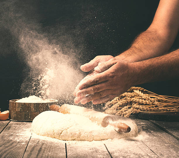 hombre preparando masa de pan sobre mesa de madera en una panadería - bread dough fotografías e imágenes de stock