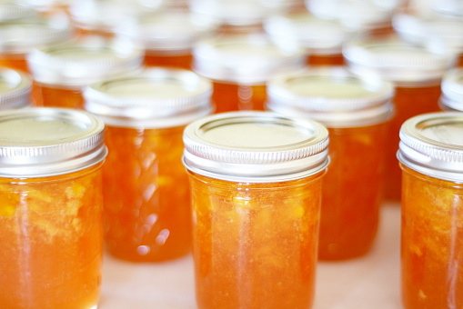 Endless rows of homemade peach jam in jars with a shallow depth of field.