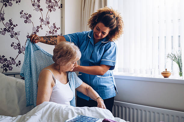 istock Home caregiver dressing senior 602319074
