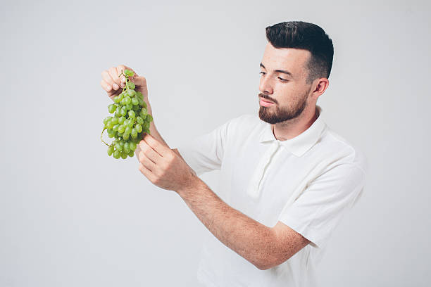 istock man holding grape, close up. concept. isolated on white 602319130