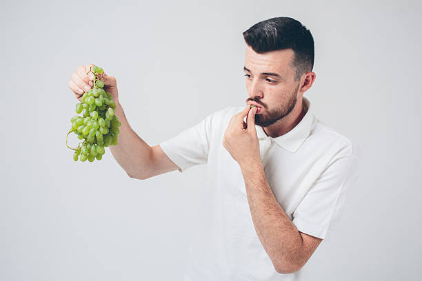 istock man holding grape, close up. concept. isolated on white 602319192