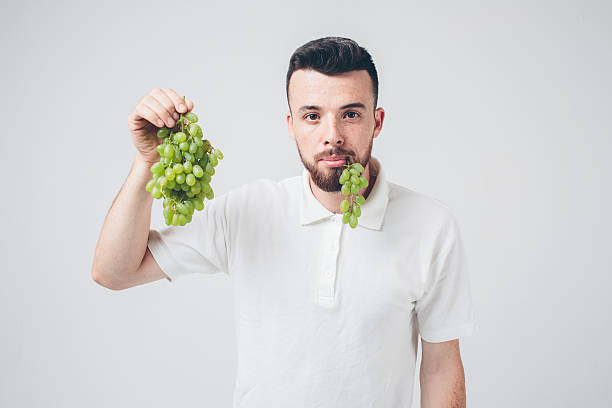 istock man holding grape, close up. concept. isolated on white 602319254