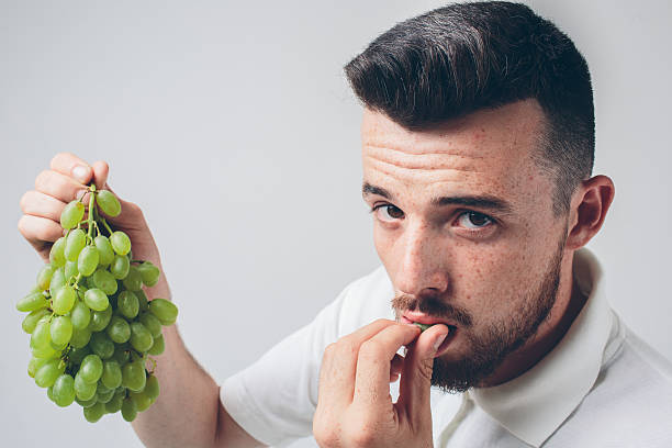 istock man holding grape, close up. concept. isolated on white 602319458