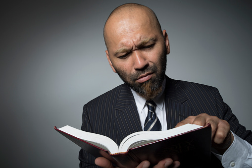 Businessman reading a book with a serious face.