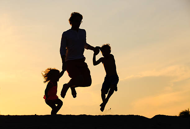 istock happy father with son and daughter jumping at sunset 602320288