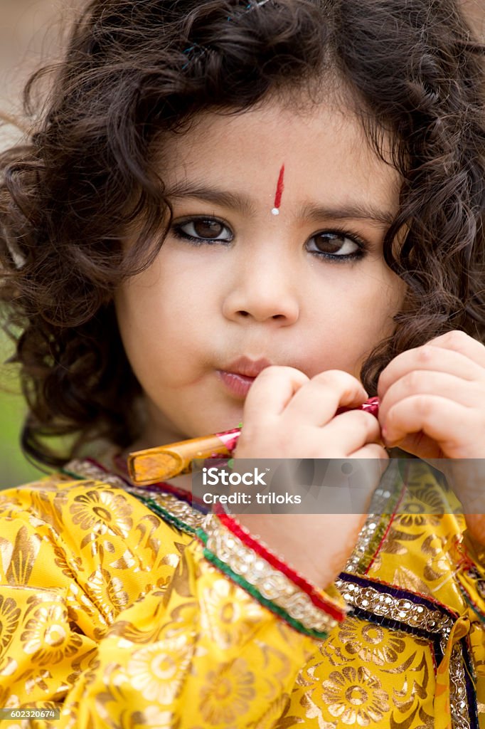 Krishna Janmashtami Child dressed as Lord Krishna on the occasion of Janmashtami and playing flute. Happy Krishna Janmashtami 6-7 Years Stock Photo