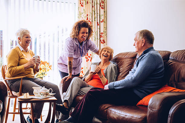 Tea and Cake in the Care Home Three seniors enjoying tea and cake in the care home. There is a caregiver laughing with them. caregivers day stock pictures, royalty-free photos & images
