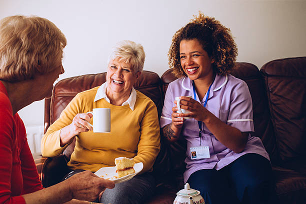 caregiver sharing tea time with her patients - community outreach home caregiver care cheerful imagens e fotografias de stock