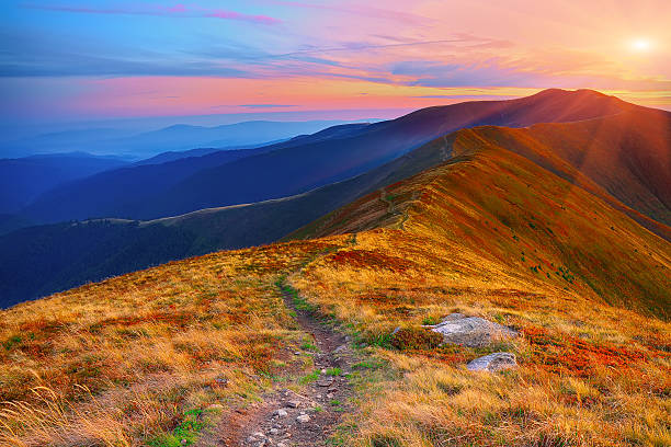istock winding road through meadows of  mountain range at sunset 602323072