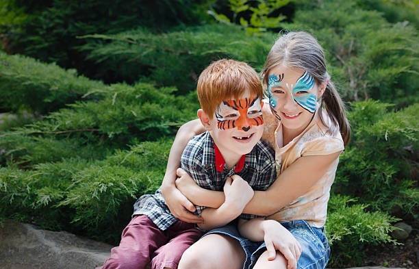 glückliche kinder, junge und mädchen mit gesichtsfarbe im park - bemalte gesichter stock-fotos und bilder