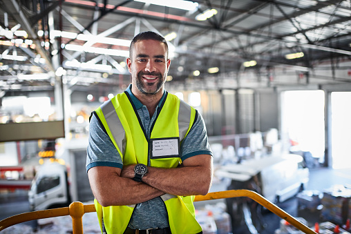 Portrait of a warehouse worker standing with his arms crossed in a large warehouse