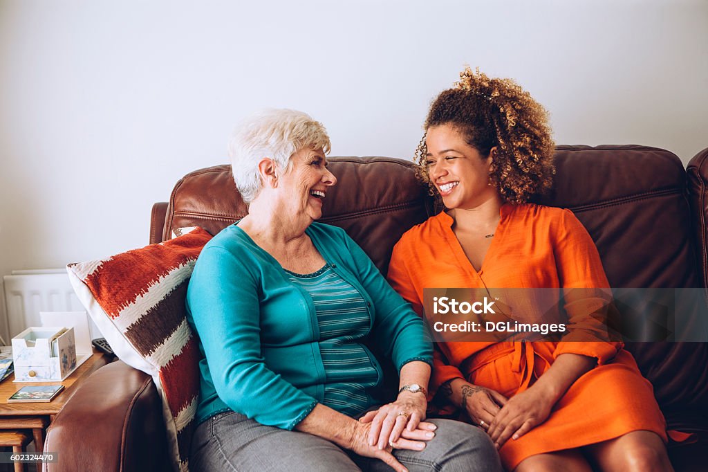 Giggles with Grandma Senior woman enjoying a laugh with her granddaughter. They are sitting on the sofa together. Senior Adult Stock Photo