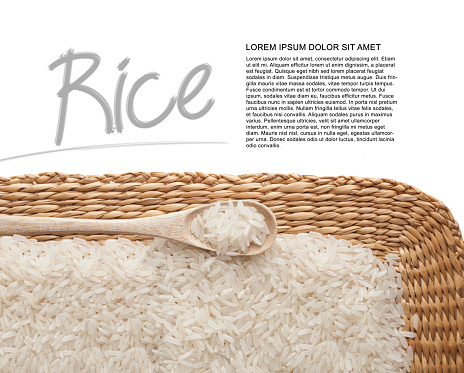 Asian uncooked white rice in a wooden spoon on a background of straw.