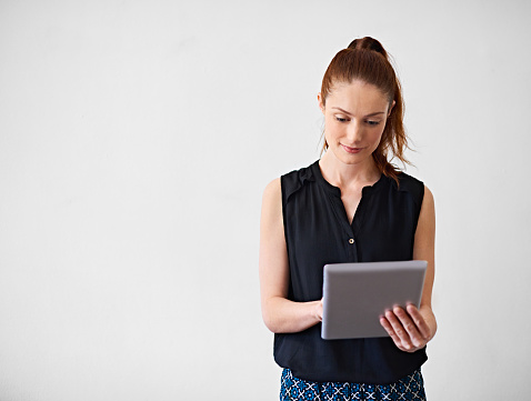 Studio shot of a young woman using a digital tablet against a gray background