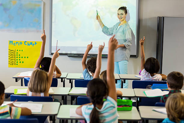 Teacher teaching schoolchildren using projector screen Smiling female teacher teaching schoolchildren using projector screen in classroom teacher projector stock pictures, royalty-free photos & images
