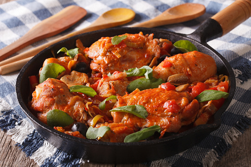 Italian food: chicken with tomato and vegetables close-up in a frying pan. horizontal