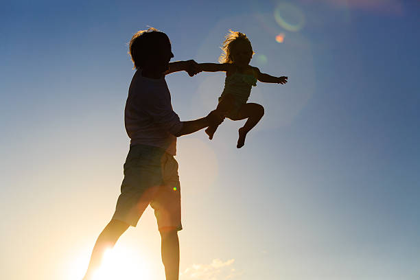 istock Father and little daughter playing silhouettes at sunset 602331802
