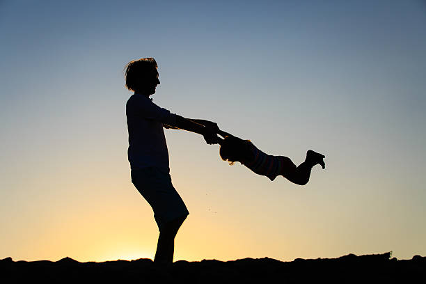 istock Father and little daughter silhouettes play at sunset 602333272