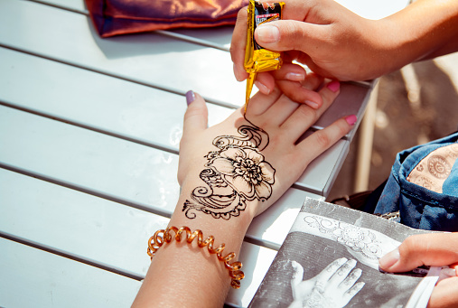 Zaporizhia/Ukraine- September  3, 2016: Charity festival for children – City of professions . Applying temporary henna tattoo activity.  Closeup teen girl arm - flower ornament painting process. 