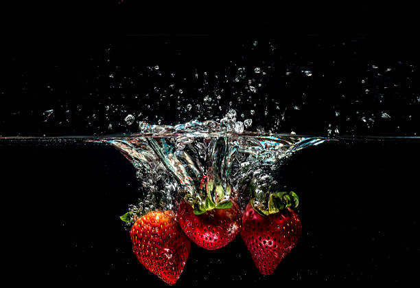 two strawberries into water - wet strawberry macro fruit imagens e fotografias de stock