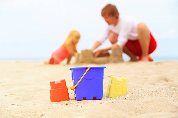 istock father and little daughter play with sand at beach 602336898