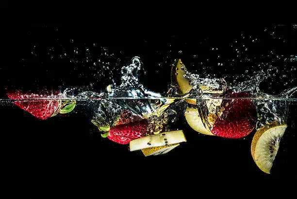 An image of strawberry and kiwi fruit splashing into water