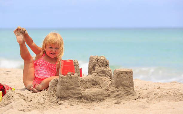 istock cute little girl play with sand on beach 602336946