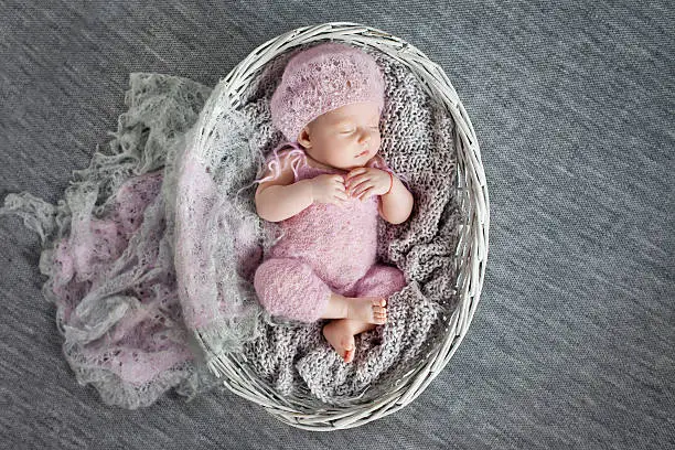 Photo of Beautiful little newborn girl 1 month sleeps in wattled basket