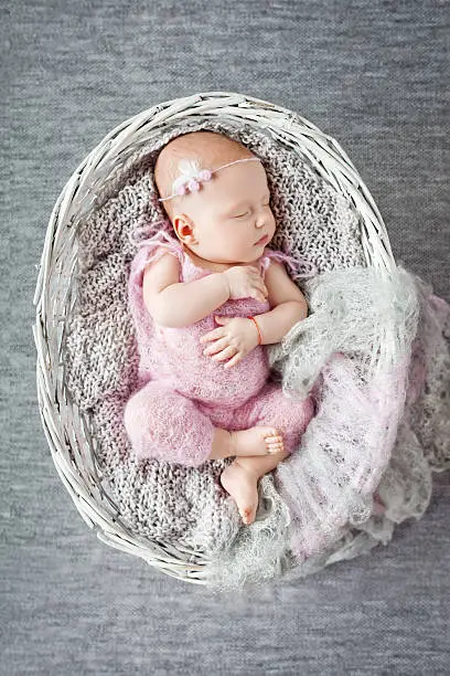 Photo of Beautiful little newborn girl sleeps in wattled basket
