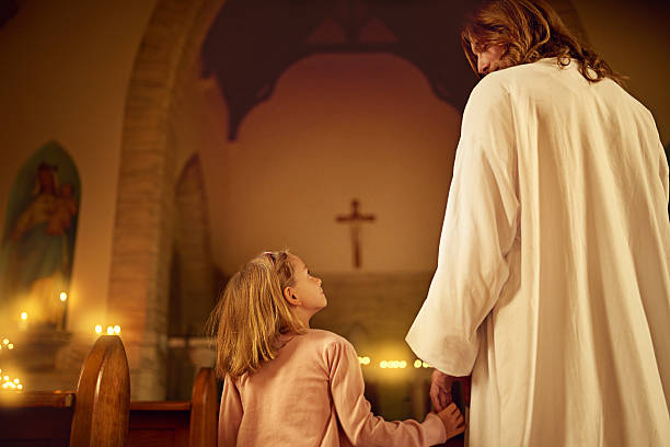 Cropped shot of a little girl holding hands with Jesus while standing inside a church