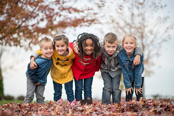 Elementary Children Playing Outside at Recess A multi-ethnic group of elementary age children are playing outside on a fall day. They are standing in a row and are smiling while looking at the camera. children only stock pictures, royalty-free photos & images