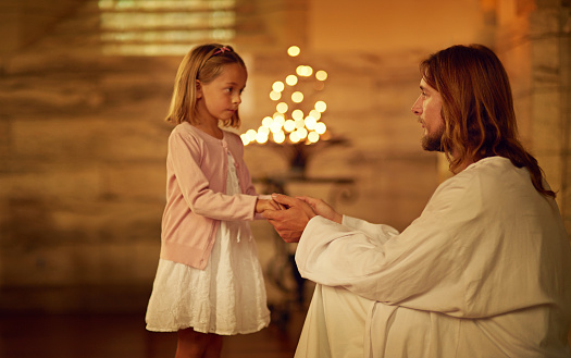 Cropped shot of a little girl holding hands with Jesus while standing inside a church