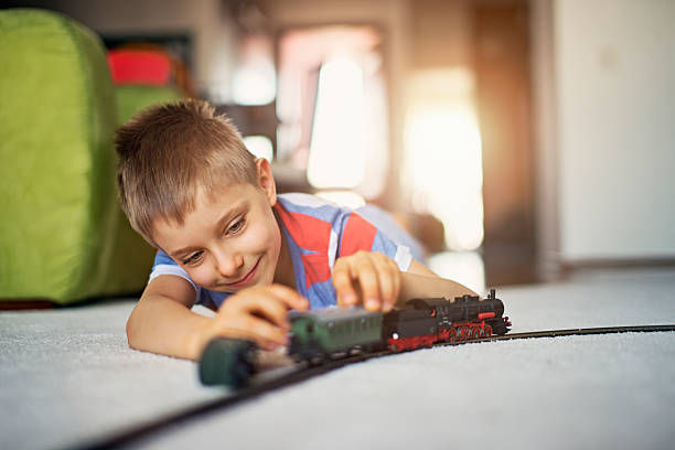 lindo niño jugando con tren miniatura - tren miniatura fotografías e imágenes de stock