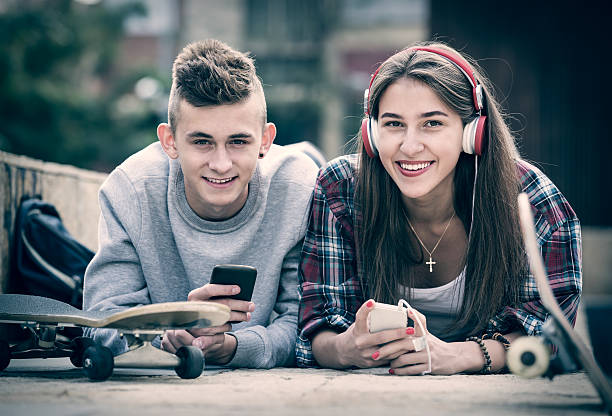 adolescente y su novia con los smartphones - video game friendship teenager togetherness fotografías e imágenes de stock