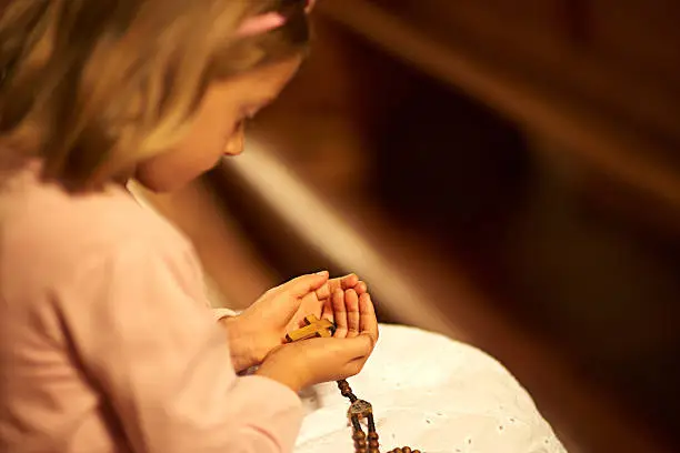 Cropped shot of an unidentifiable little girl holding a wooden cross in her hands