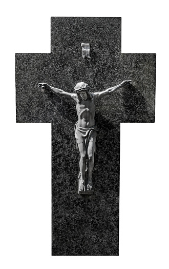 The dark gray statue of Jesus Christ hangs on a broad cross made of black marble. A religious symbol of faith, hope and spirituality. A close-up and full-frame image isolated on white.