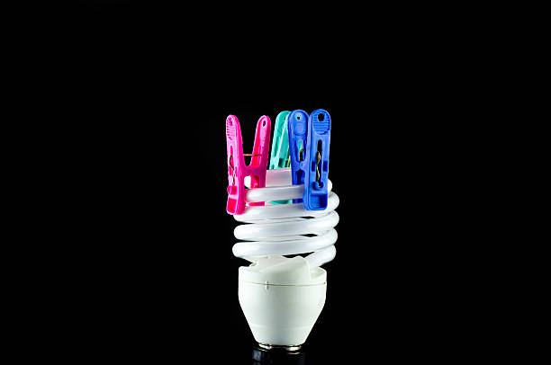 Energy saving lamp  The clothespin isolated on black background.