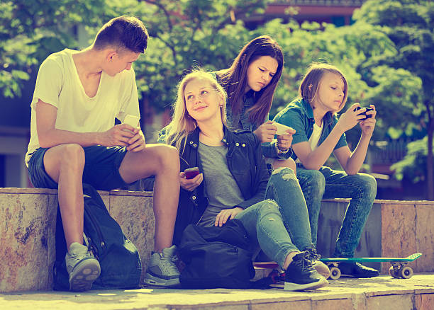 istock Friends sitting with mobile phones in park 603156032