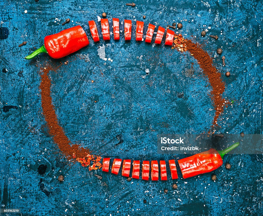 Frame of red chili Frame of sliced, ground and powdered red chile pepper over blue background. Flat lay. Color toning Apartment Stock Photo