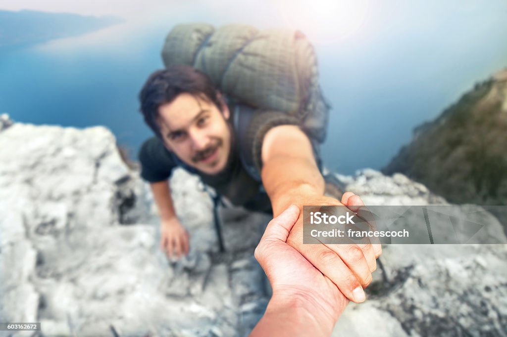 adventurers helping each other to climb the mountain Assistance Stock Photo