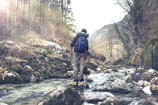 istock man feeling the forest atmosphere crossing the creek 603164132