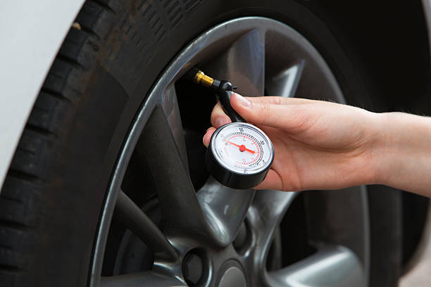 gros plan d’une femme vérifiant la pression des pneus de voiture avec un manomètre - mettre en échec photos et images de collection