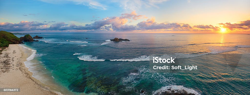 Panoramic view of tropical beach with surfers at sunset. Panoramic view of tropical beach with surfers at sunset, Kuta, Lombok island. Indonesia Panoramic Stock Photo